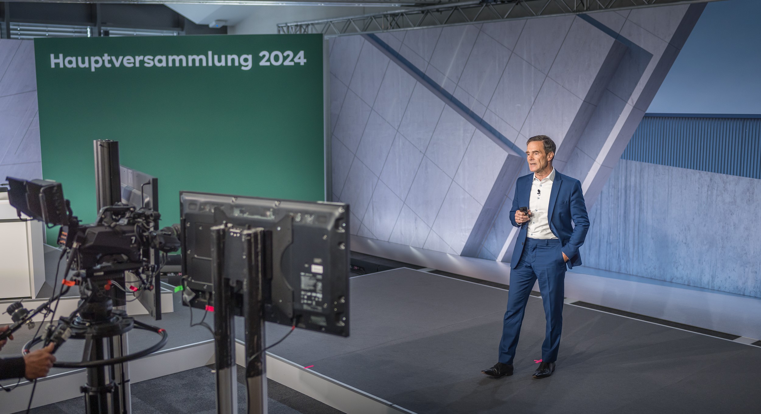 Dr Dominik von Achten standing on a stage in front of monitors