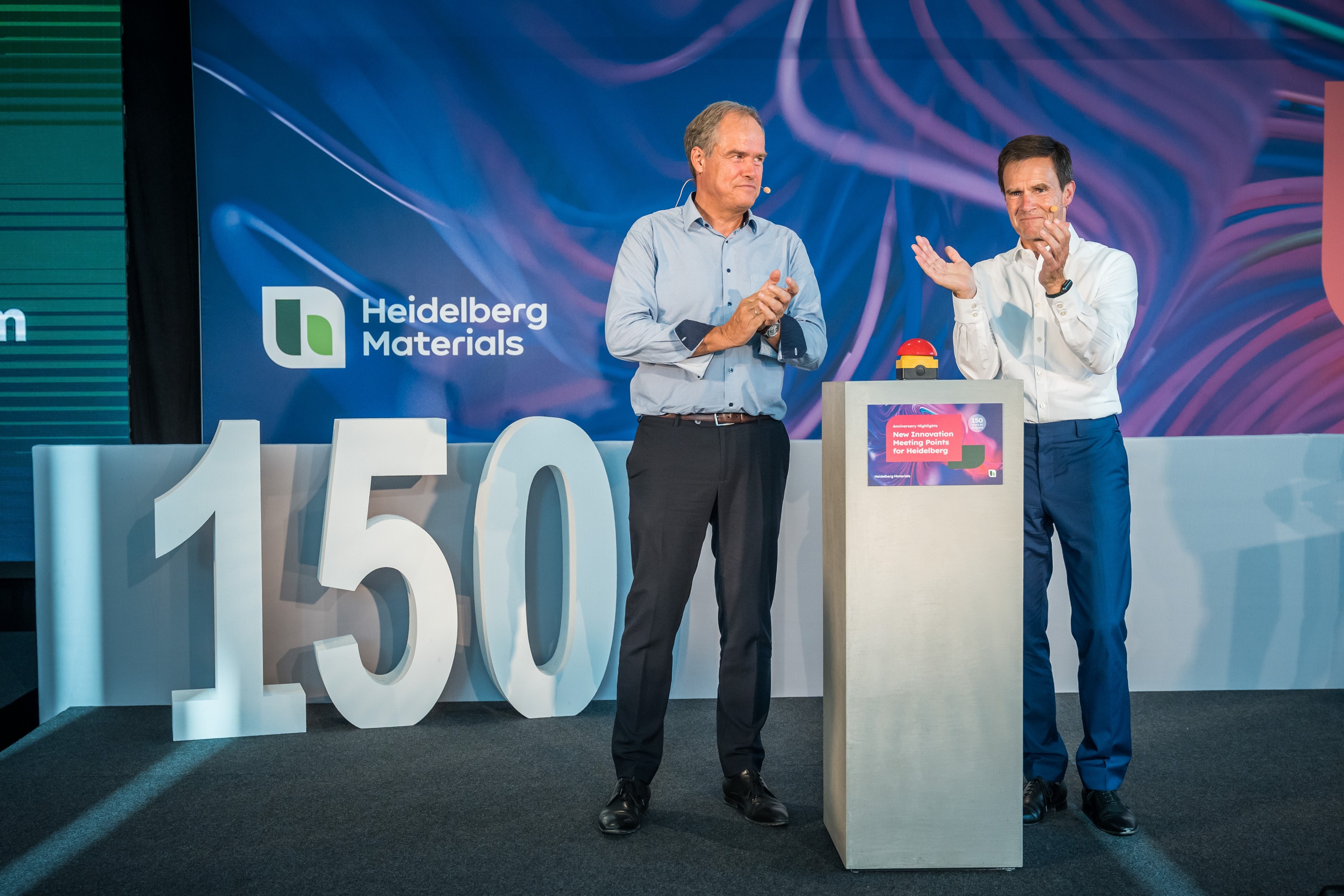 Dr Dominik von Achten, CEO of Heidelberg Materials, and Prof Dr Eckart Würzner, Mayor of the City of Heidelberg, standing on a stage in front of a buzzer, in the background you can read the number 150