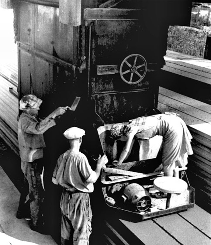 Three workers standing by a machine