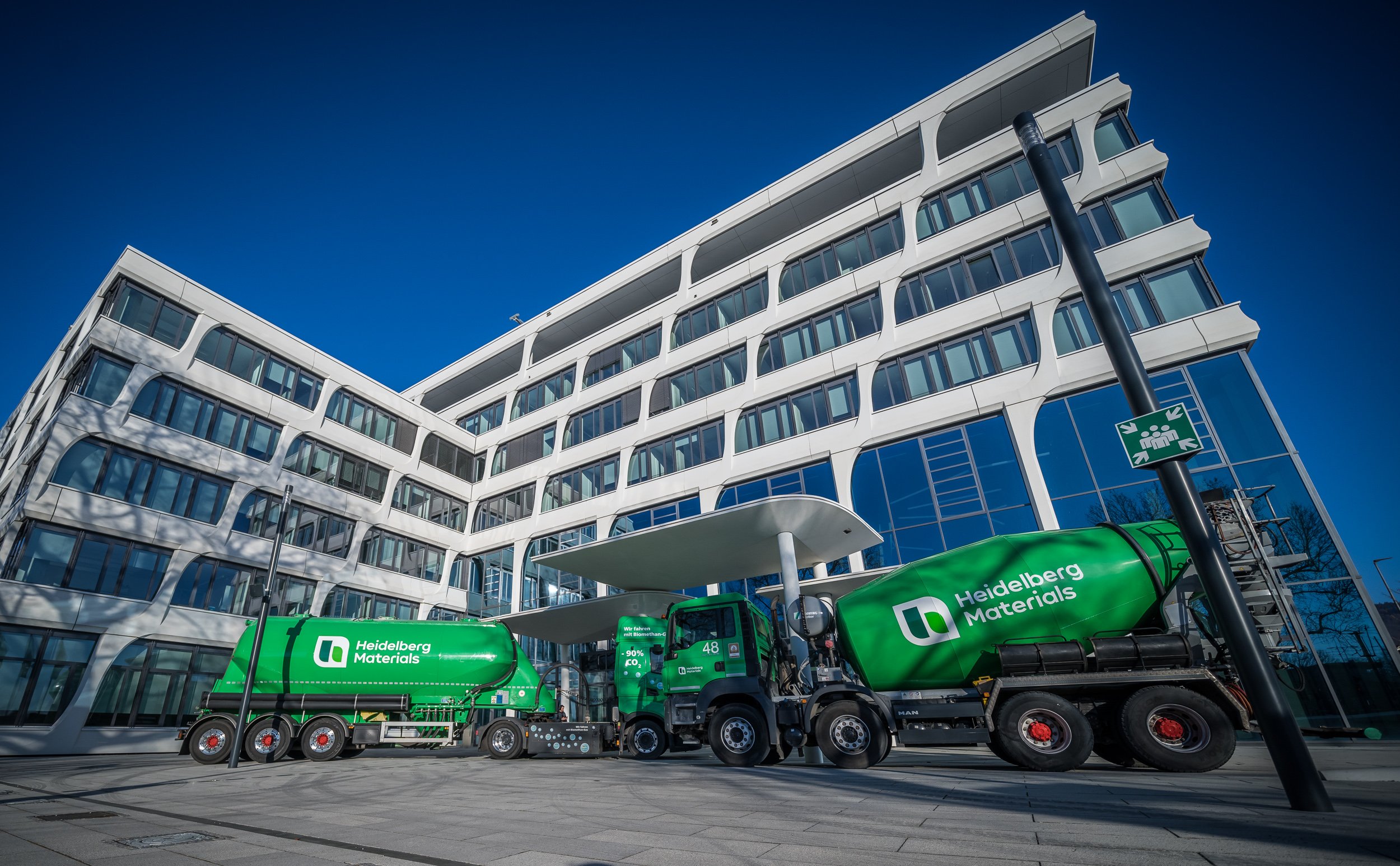 Modern office building, with ready-mix trucks labelled Heidelberg Materials in front of it
