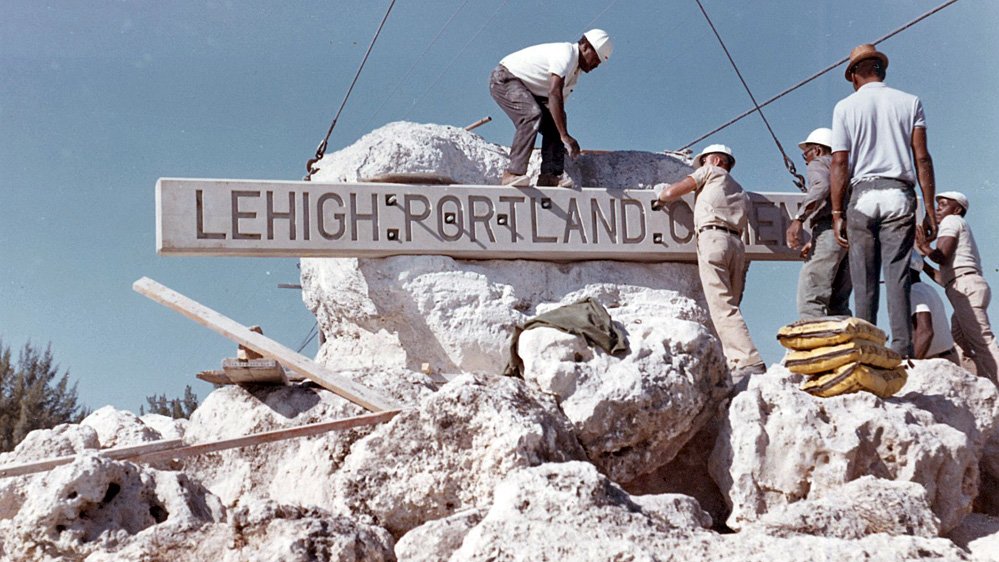 Workers on a rock put up a signboard
