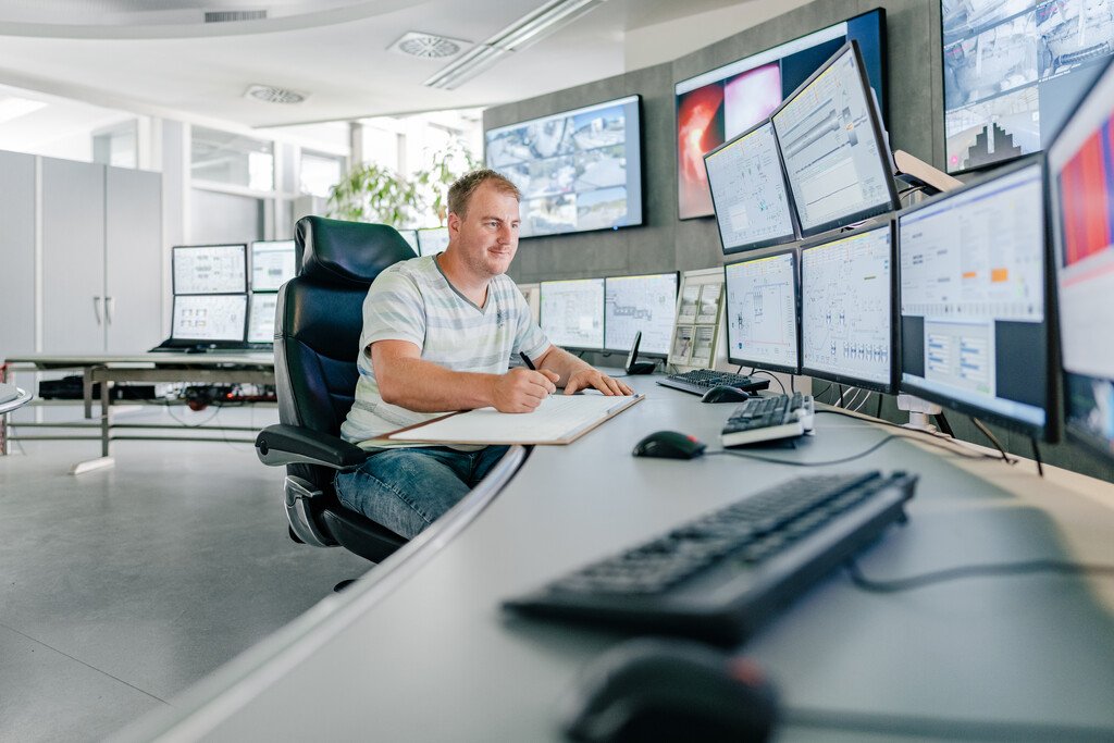 Man sitting in front of many screens in a control room