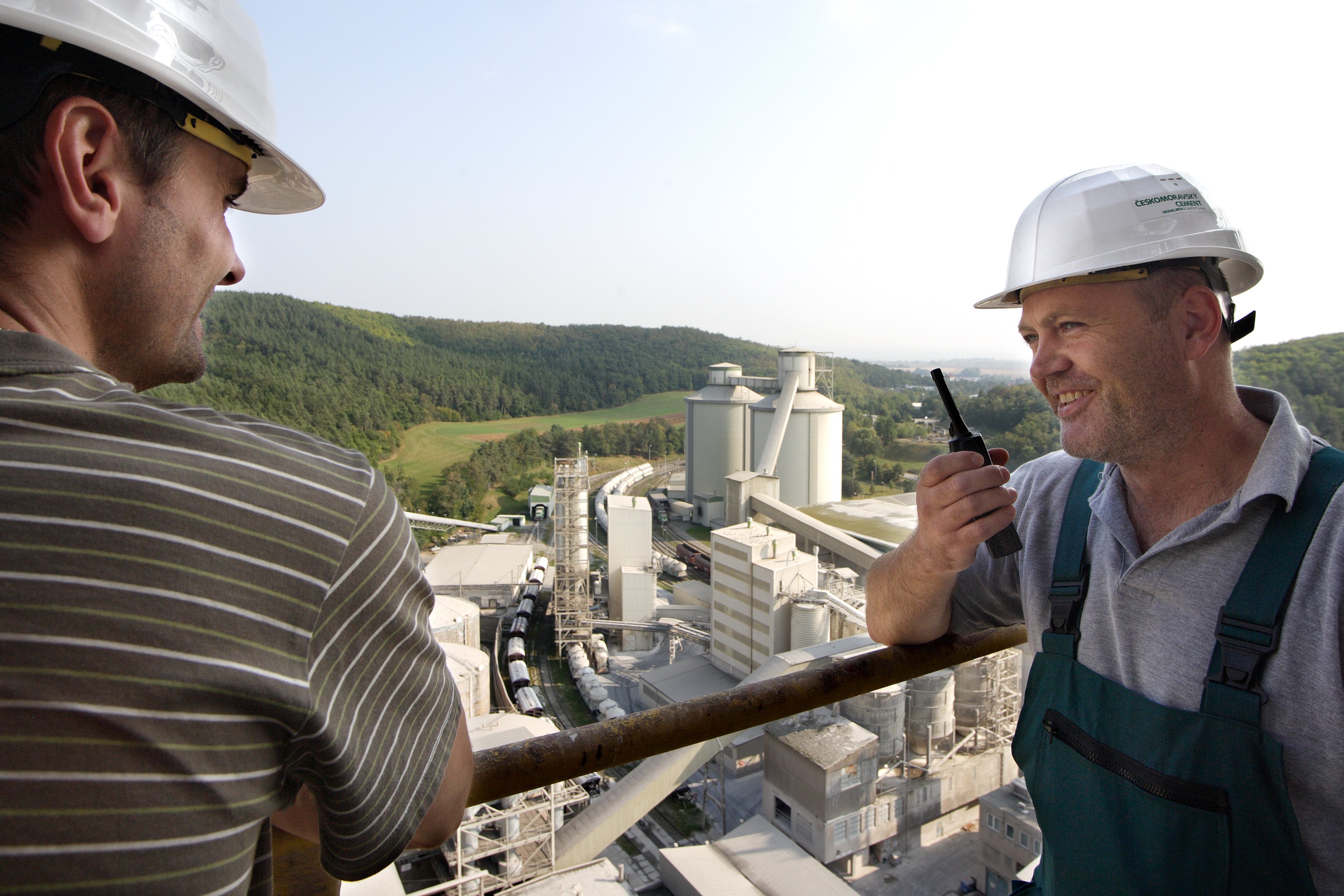Two men standing on a platform overlooking a cement plant