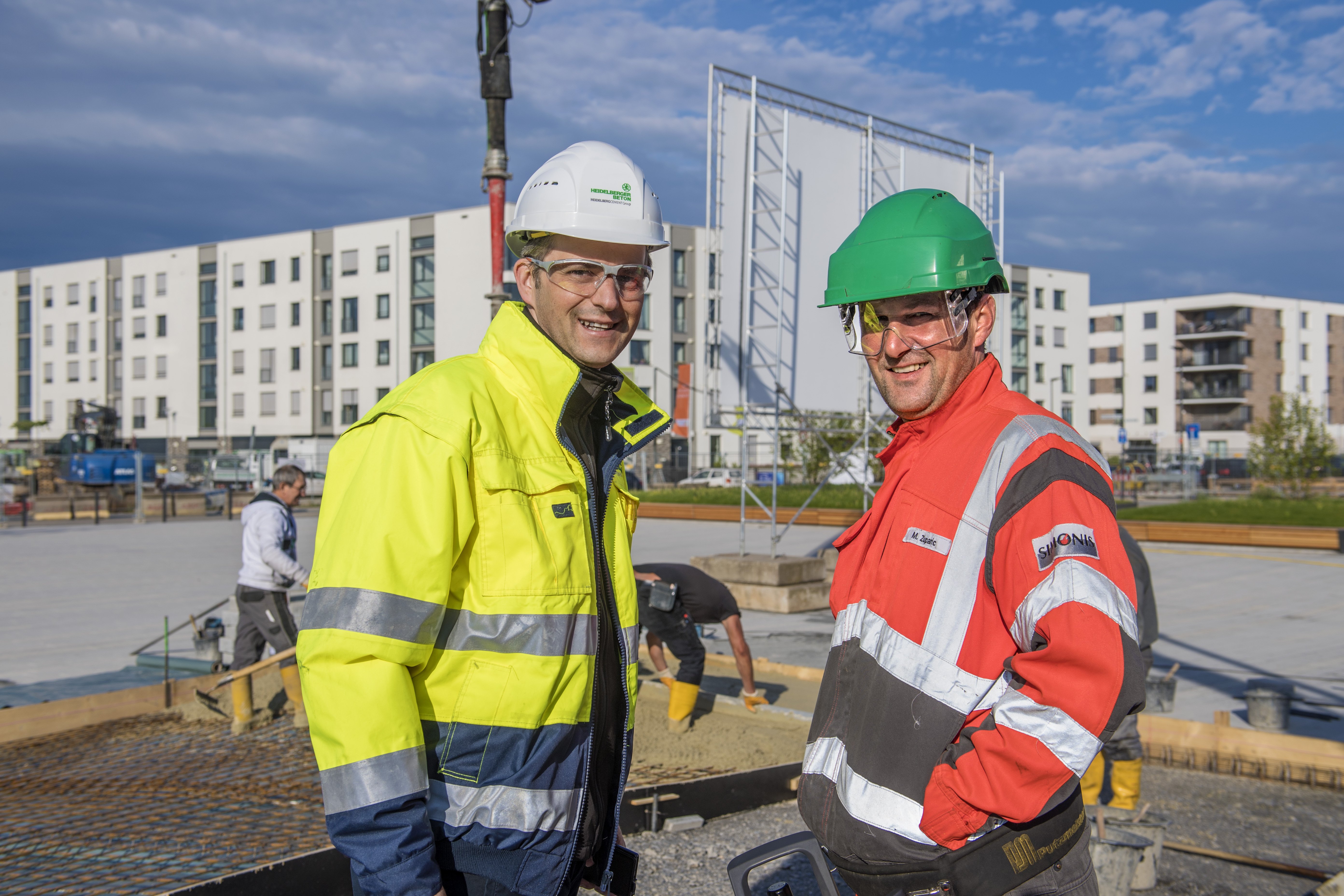 Two men with helmets standing on a construction site