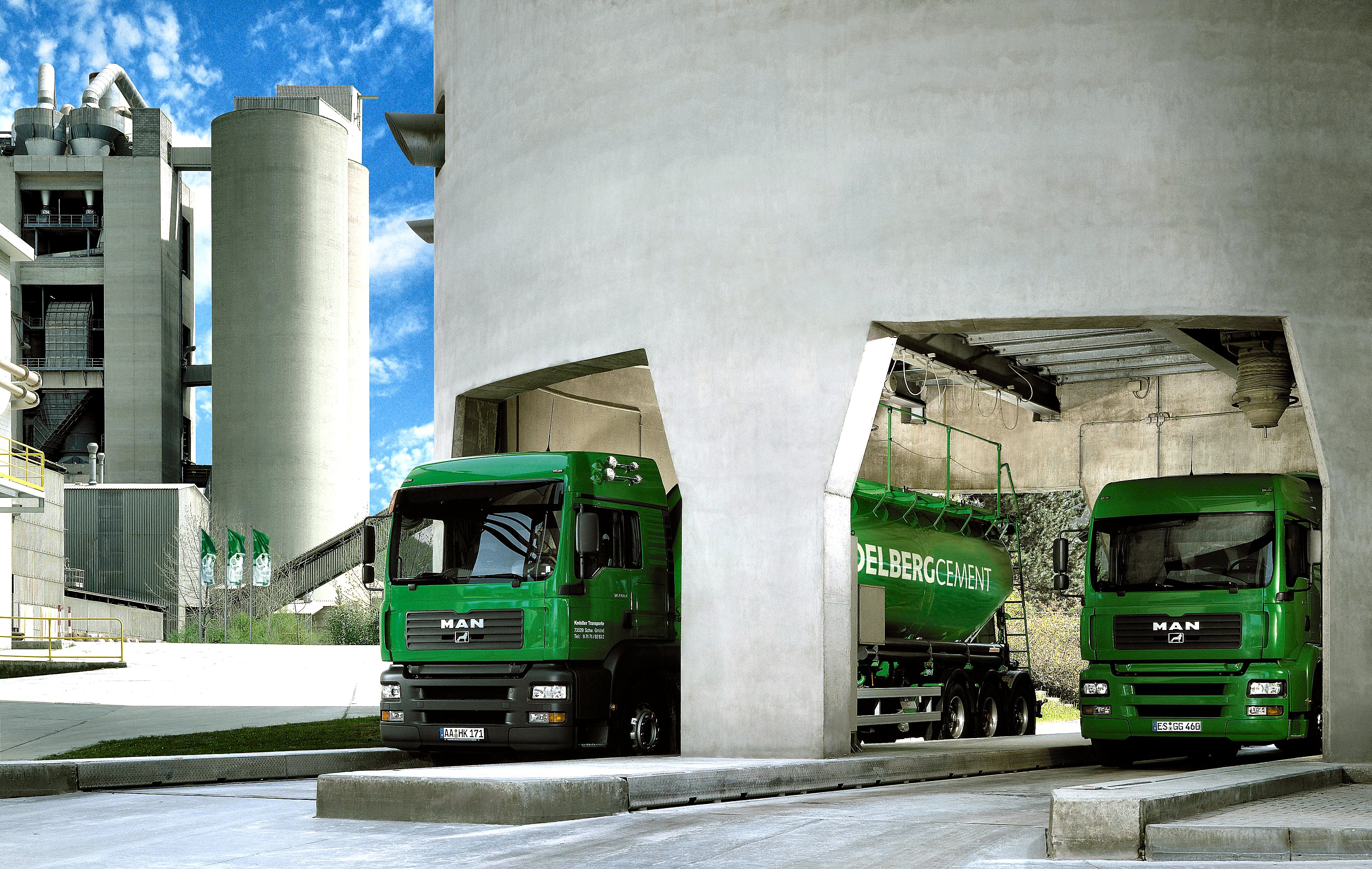 Two cement lorries are driving through a cement plant.