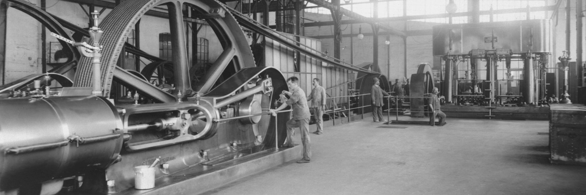 In an industrial hall workers are working on a steam engine