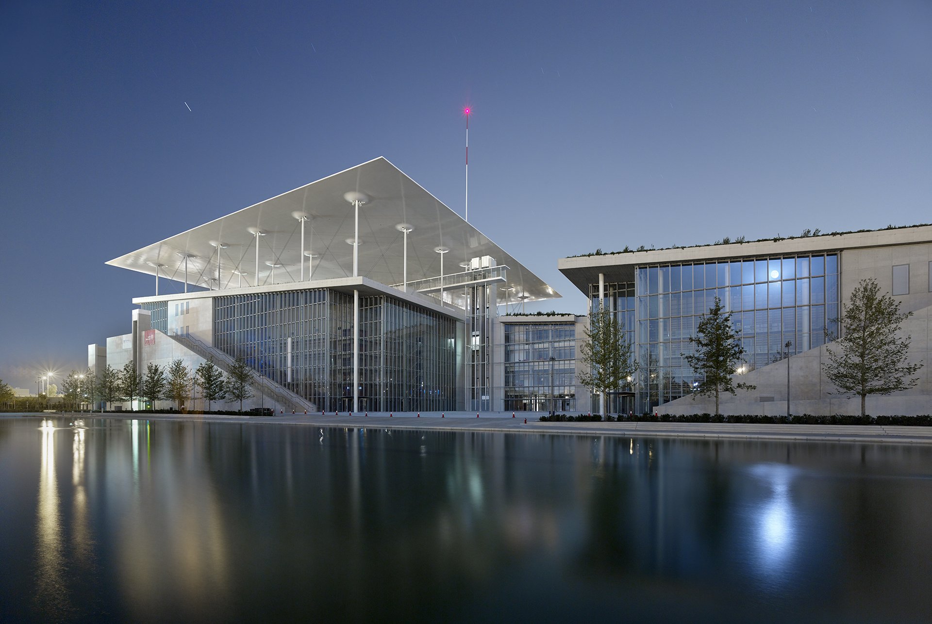 Asymmetrical glass buildings beside a river.