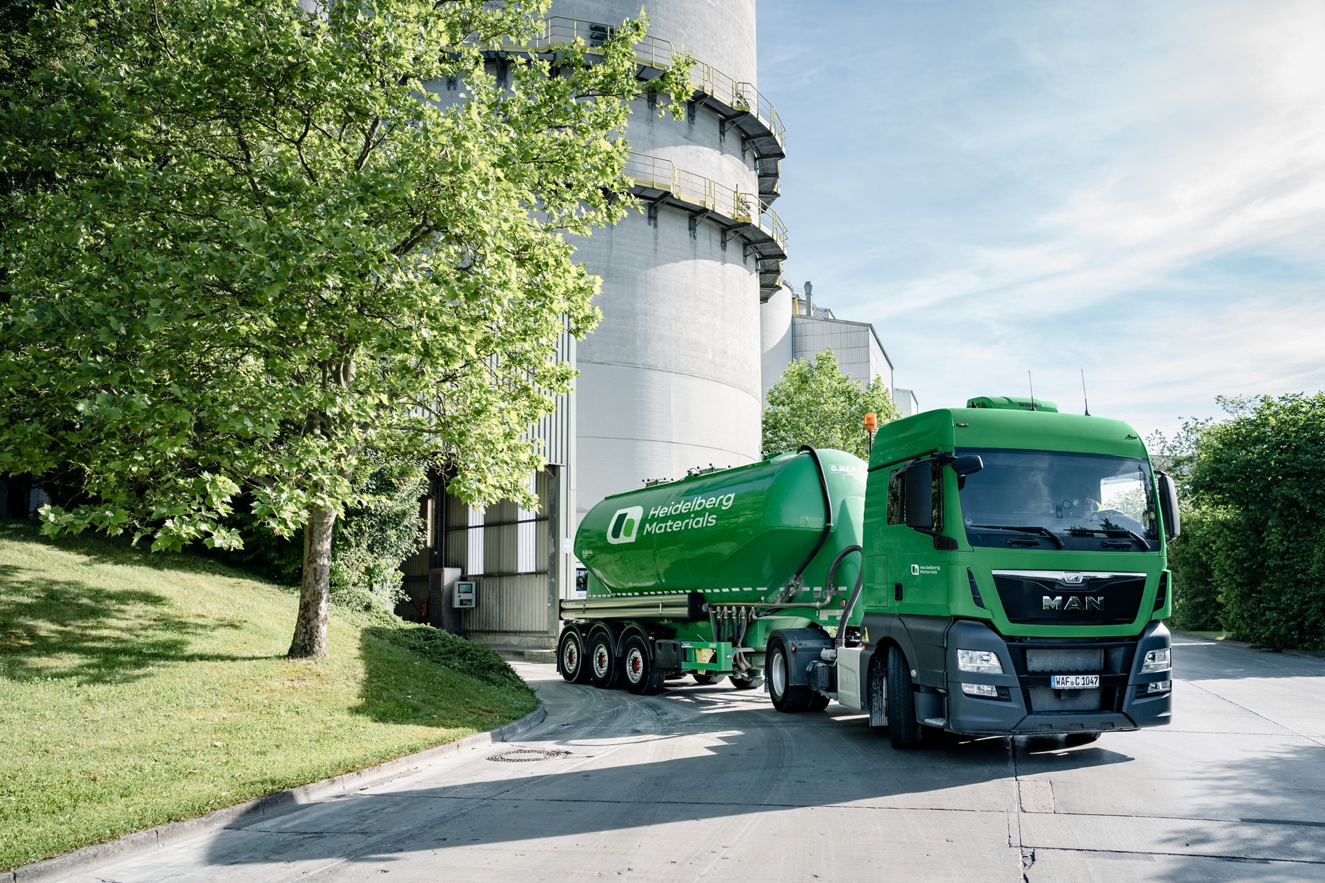 Green silo truck in front of a cement plant