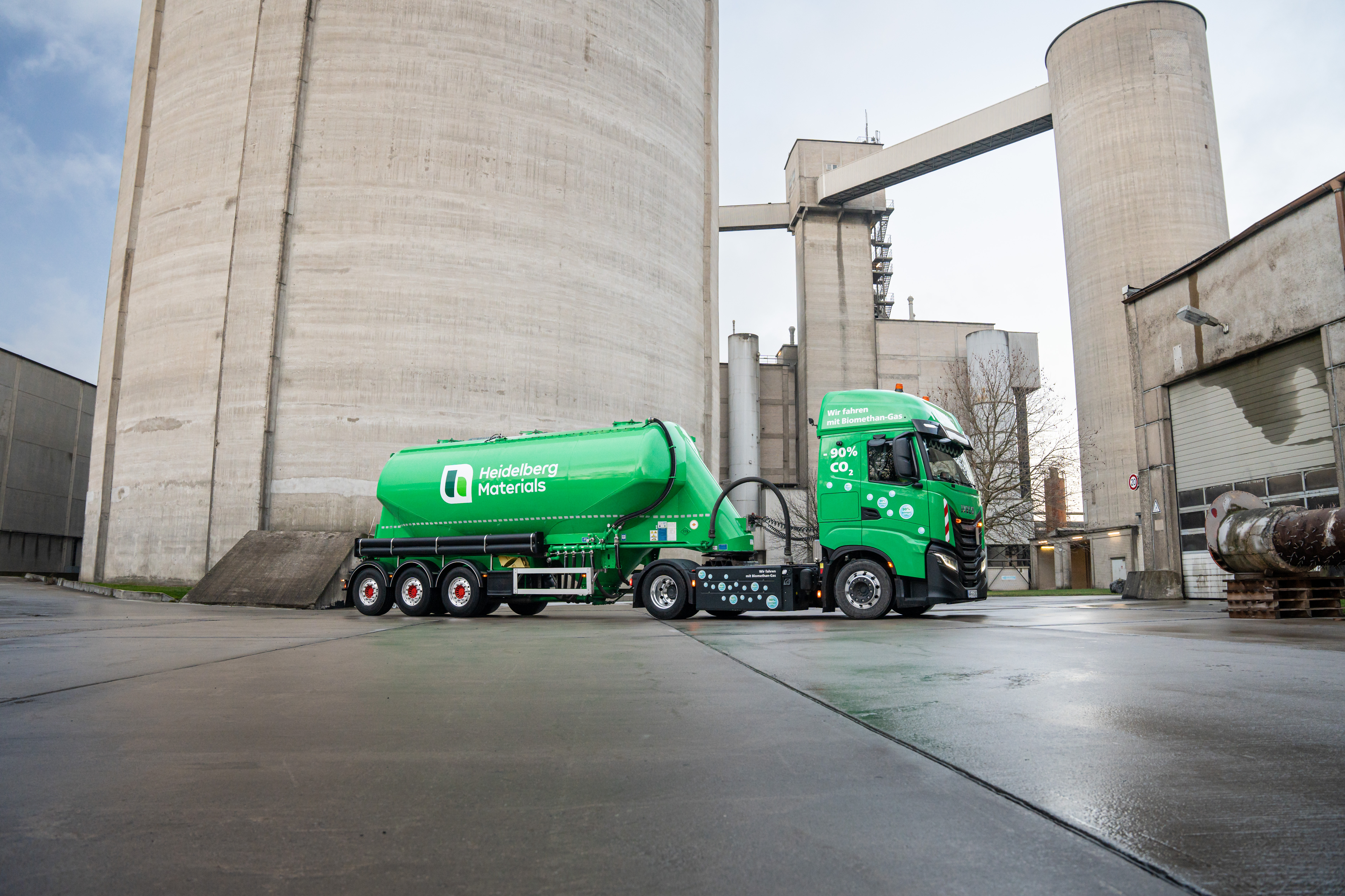 Green silo trailer in front of an industrial building