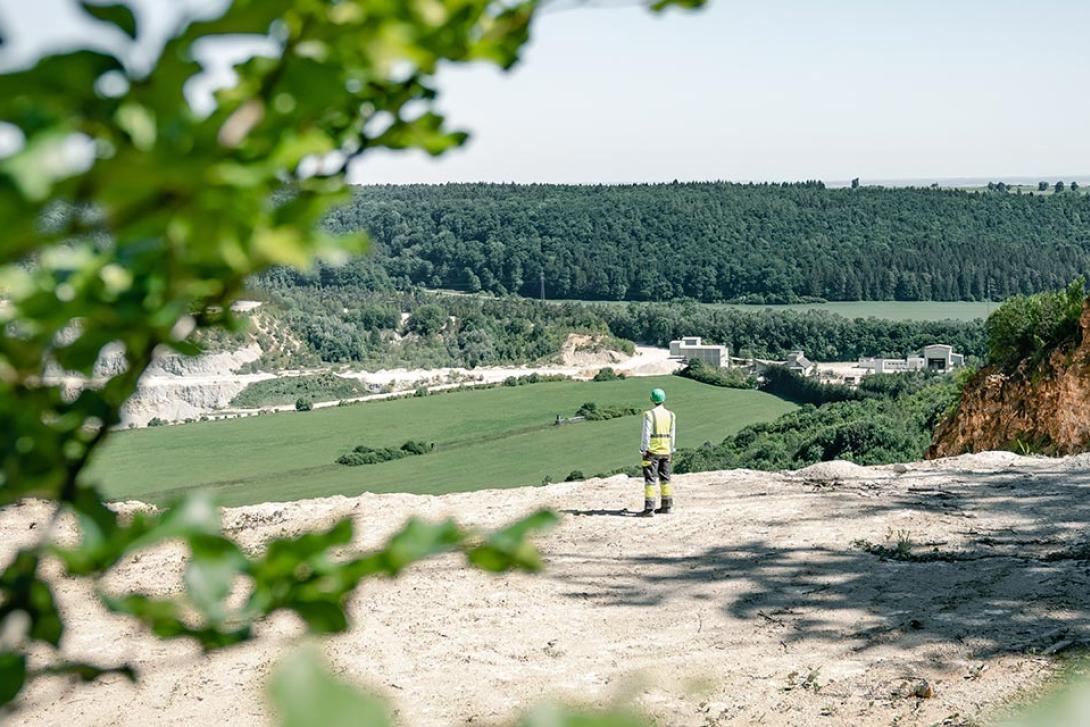 Person in protective clothing stands at the edge of a quarry and looks into nature