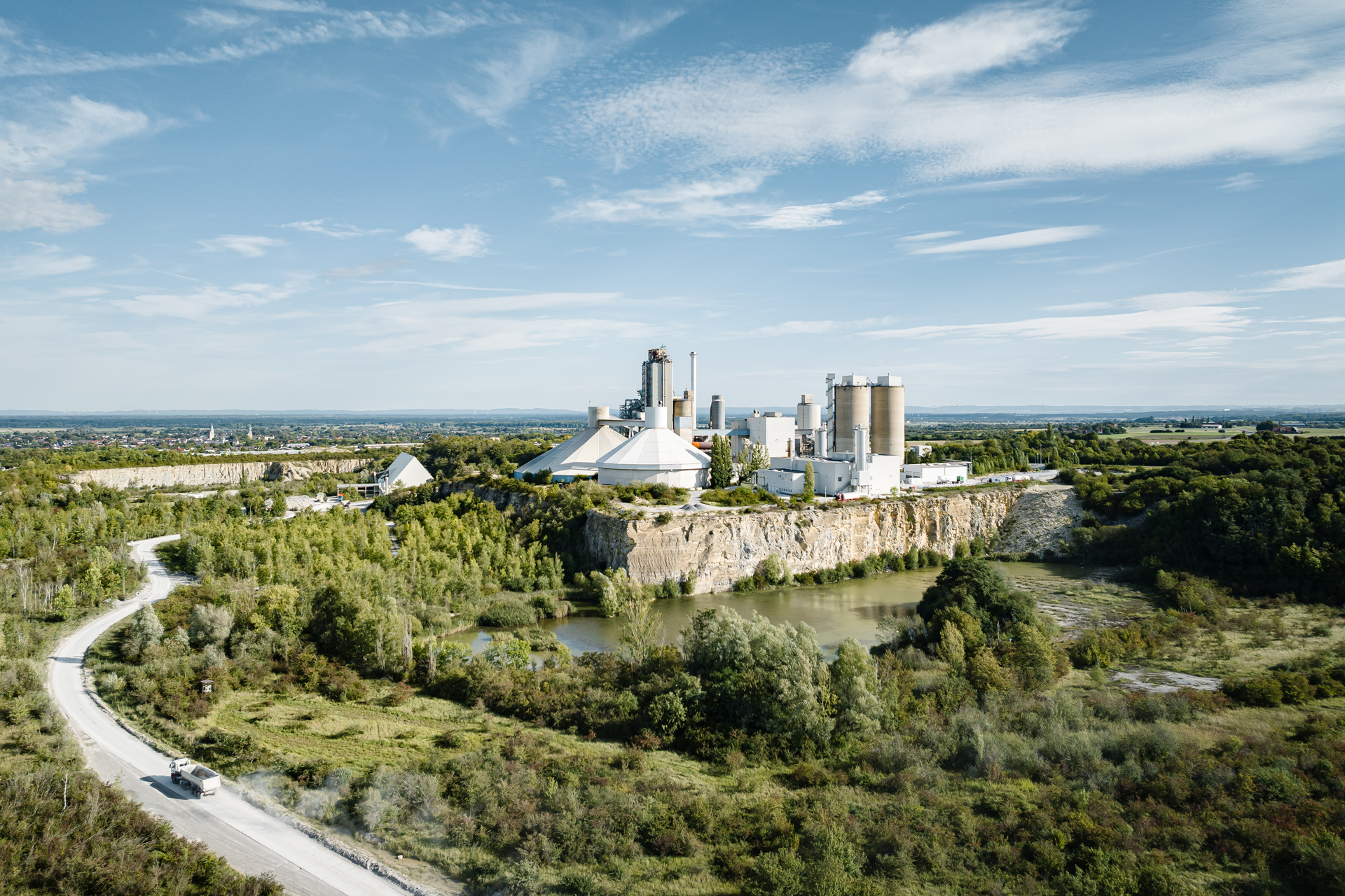 Cement works in a green landscape, a road in front of it