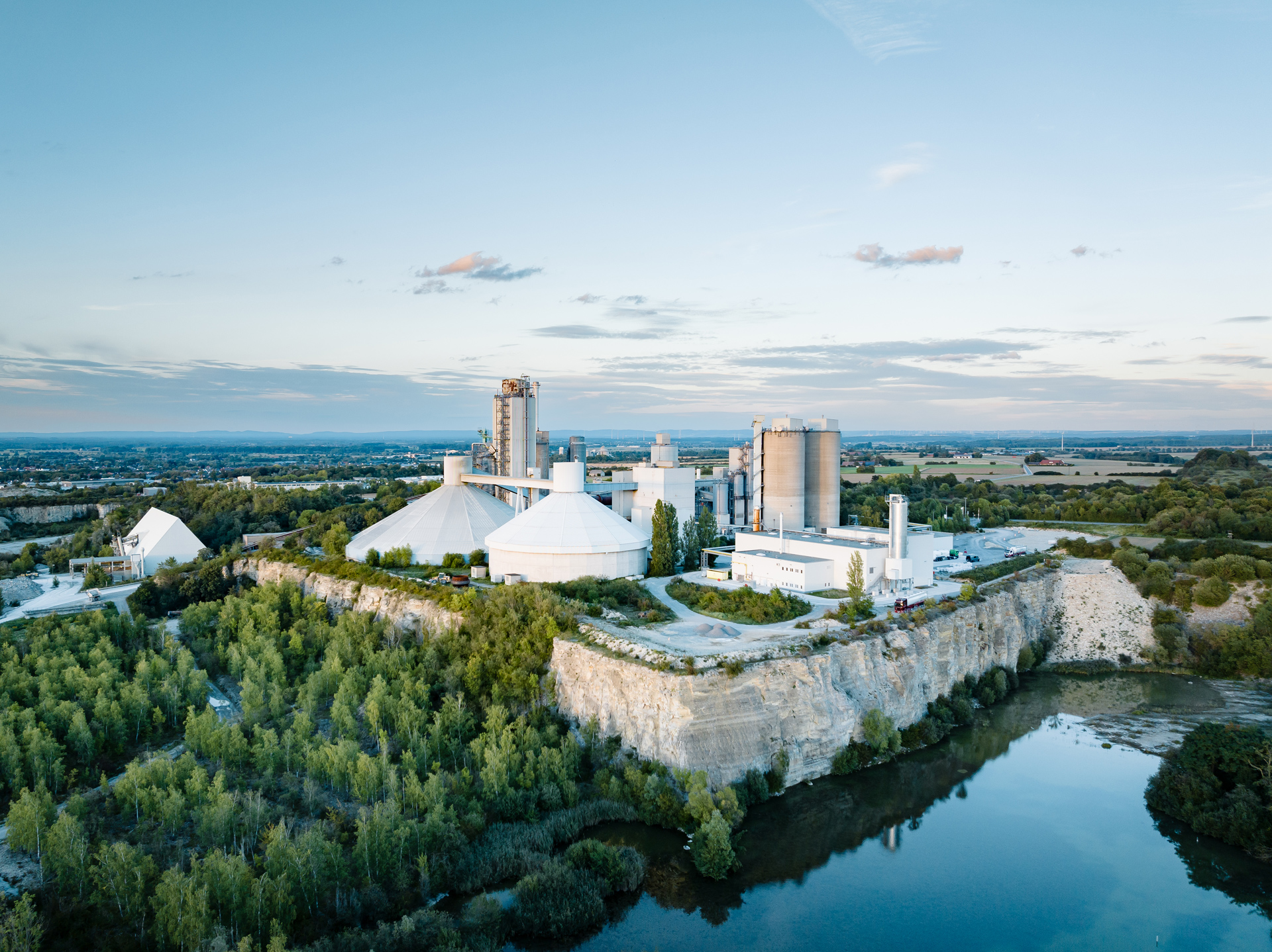 Cement works in a green landscape, water in front of it