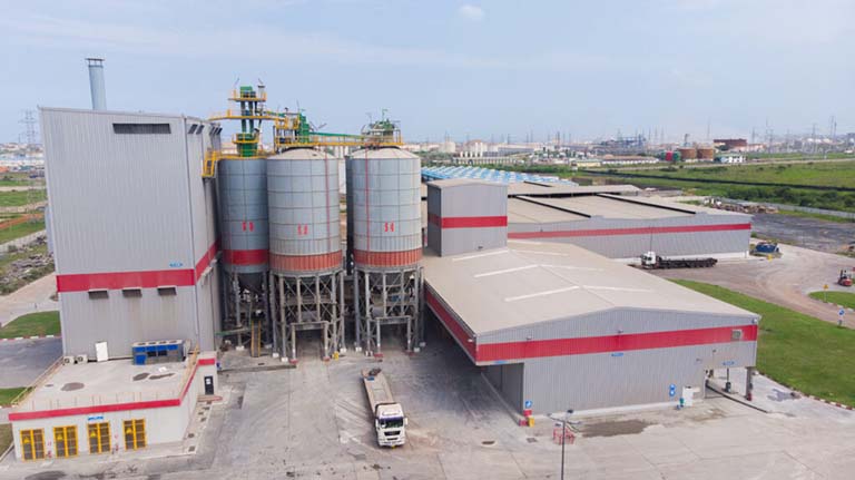 Industrial buildings with silos, all grey with a red horizontal stripe 