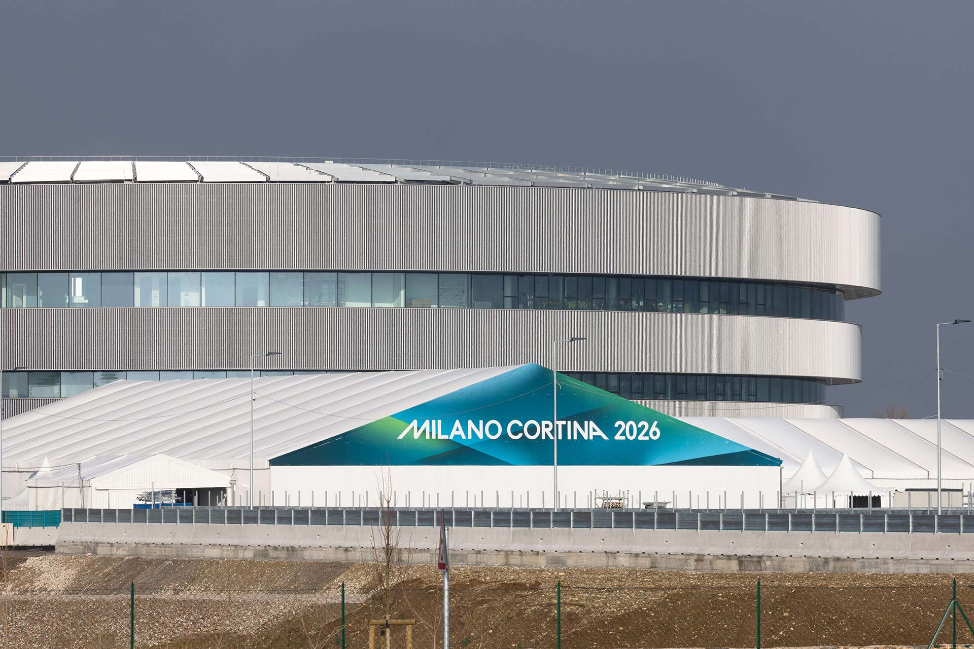 Modernes, kreisförmiges Gebäude mit großen Glasflächen und Metallverkleidung.