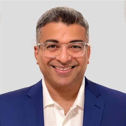 Man wearing a blue blazer over a white collared shirt.