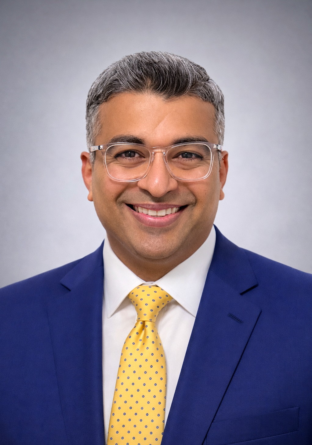 Nimit Kamdar in einem blauen Anzug mit gelber, gepunkteter Krawatte.