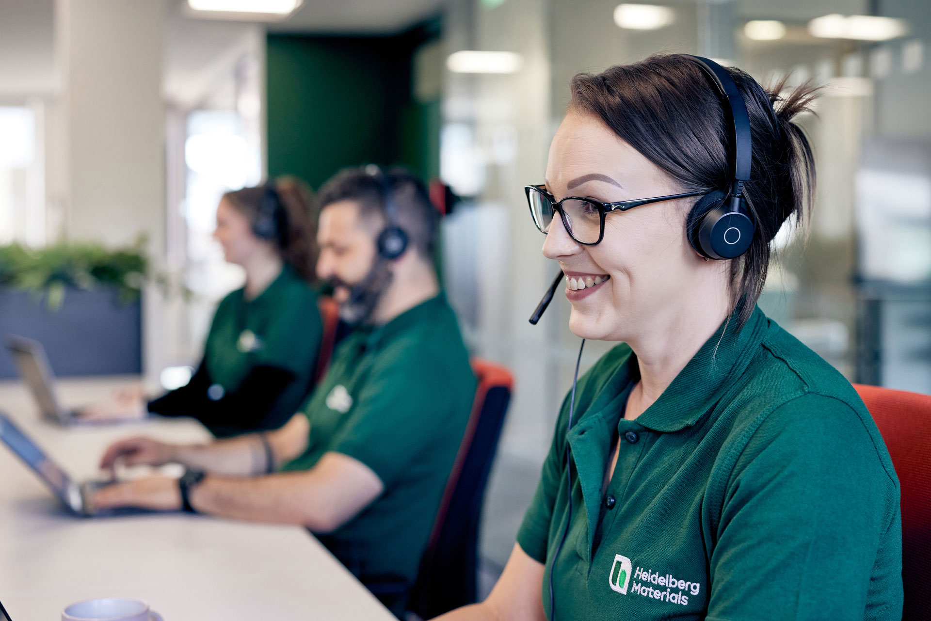 Customer support employees wearing headsets working at Heidelberg Materials office.