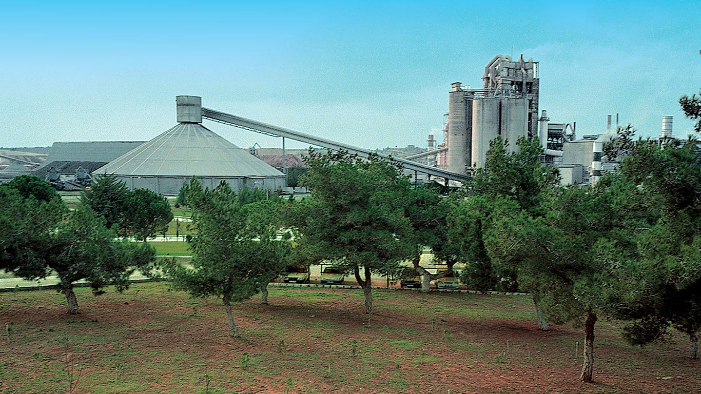 Zementwerk mit Bäumen im Vordergrund