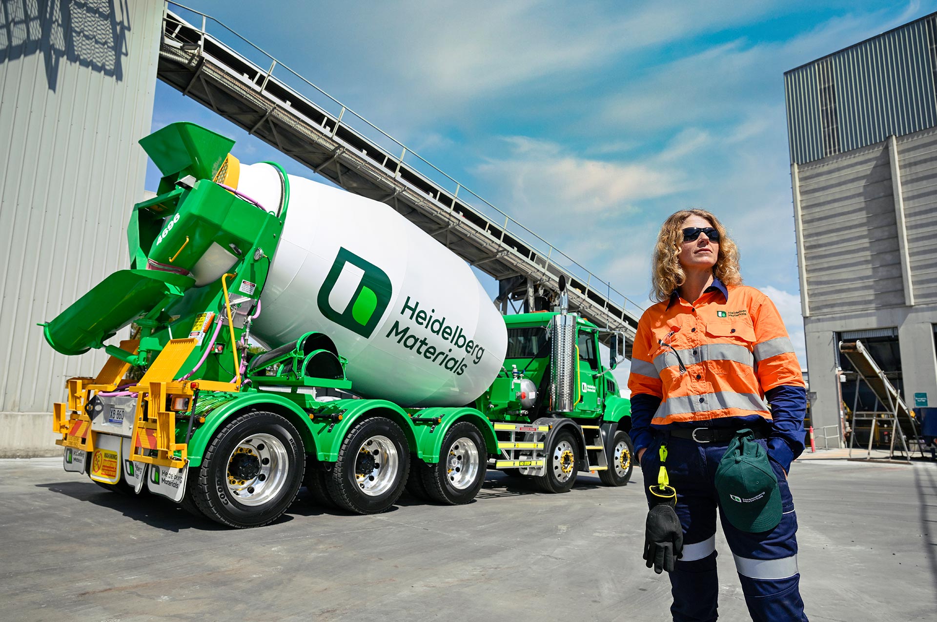 A construction worker stands near a Heidelberg Materials branded ready-mixed truck at a cement plant.
