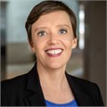 A professional individual smiling in a corporate office setting.