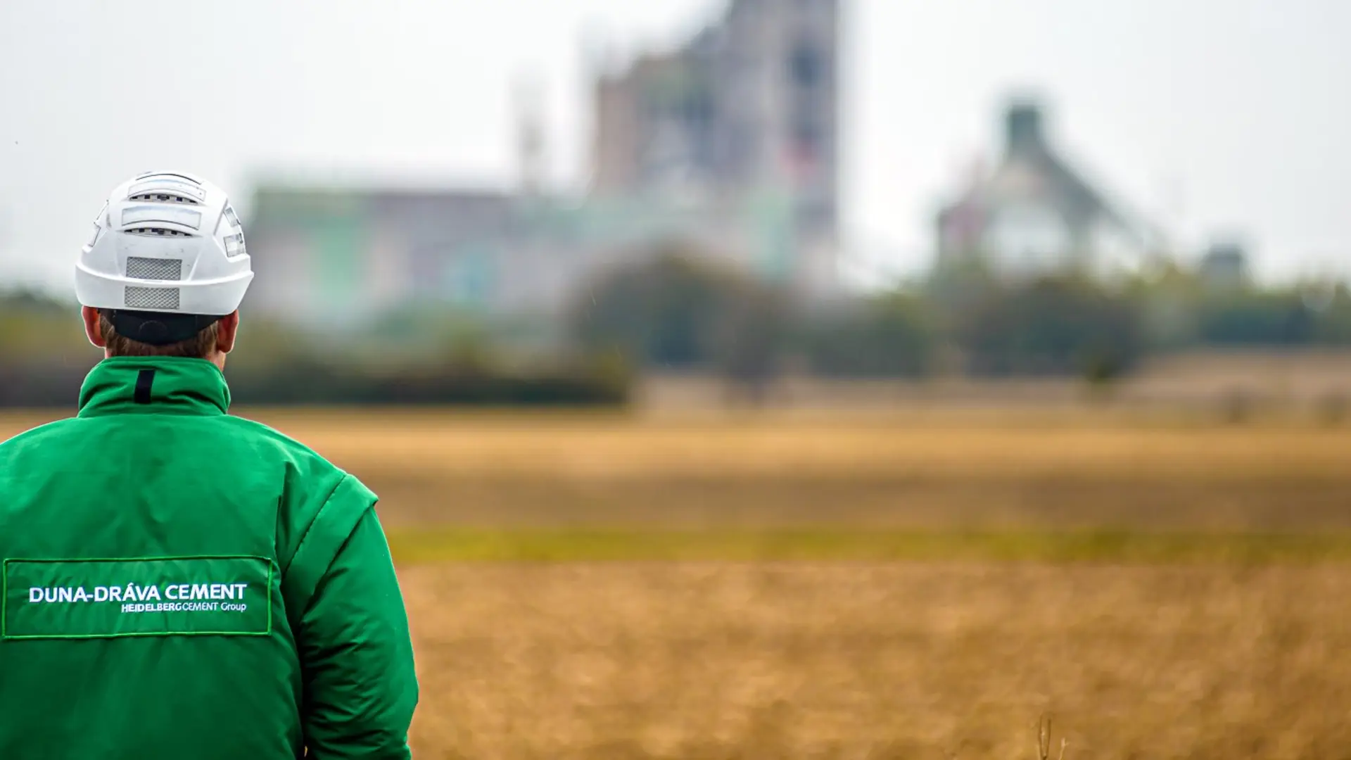A man with a helmet is looking at a cement plant