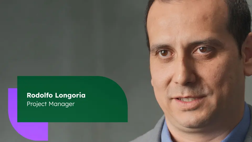 Close-up of a man with dark short hair in front of a exposed concrete wall
