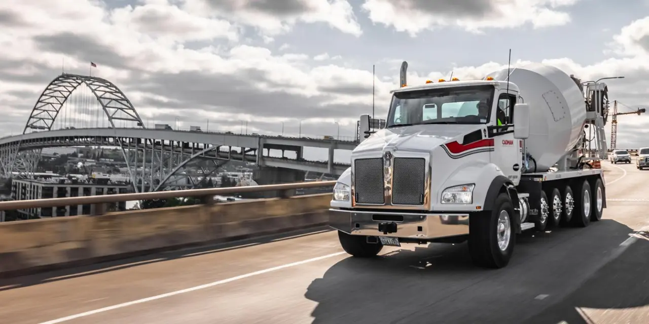 White ready-mixed truck on a road in motion blur, a bridge in the background