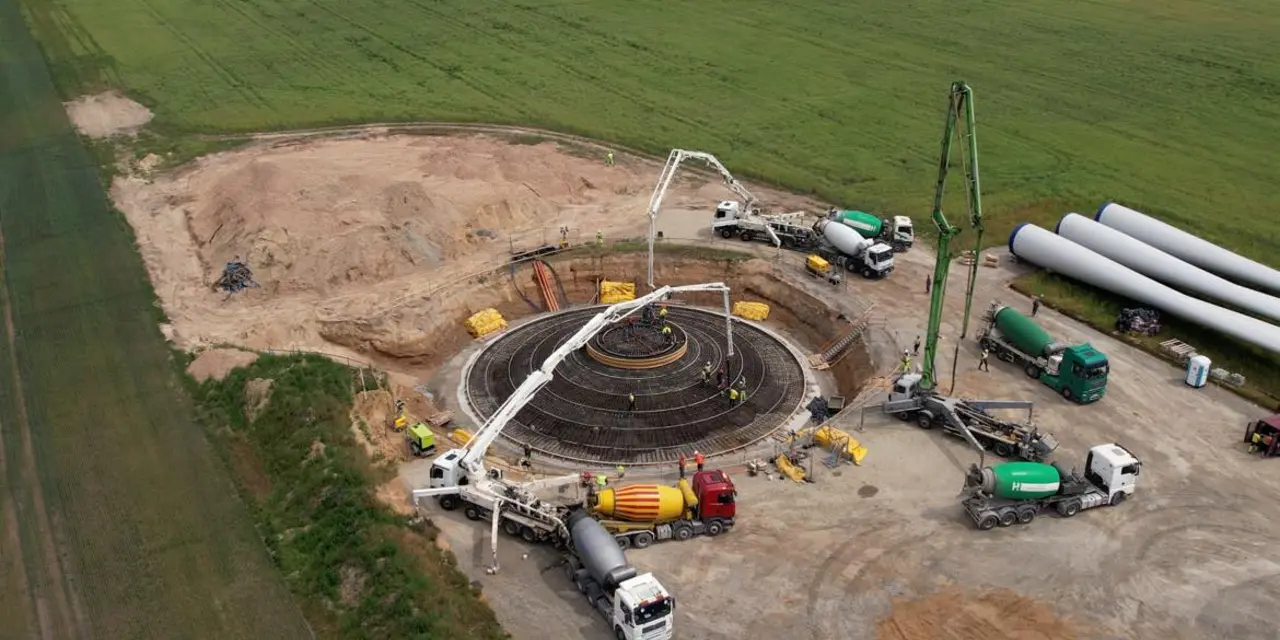 Blick von oben auf das kreisrunde Fundament eines Windrads, um das Betonpumpen stehen