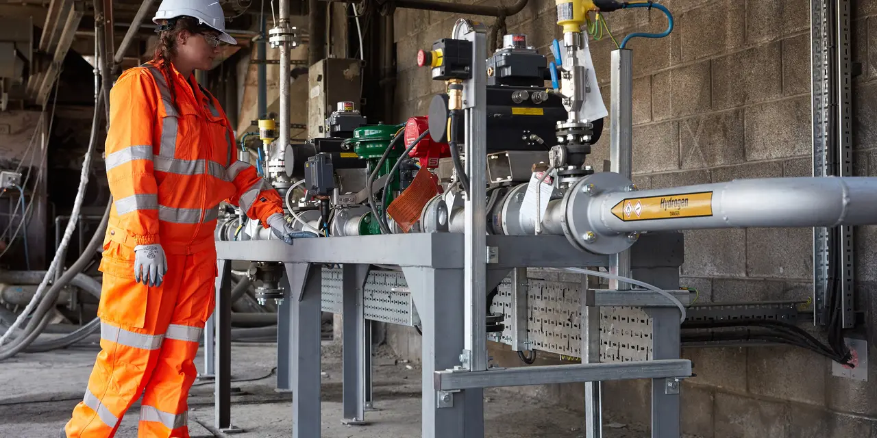 Eine Arbeiterin steht vor einer Vorrichtung, auf der Wasserstoff steht