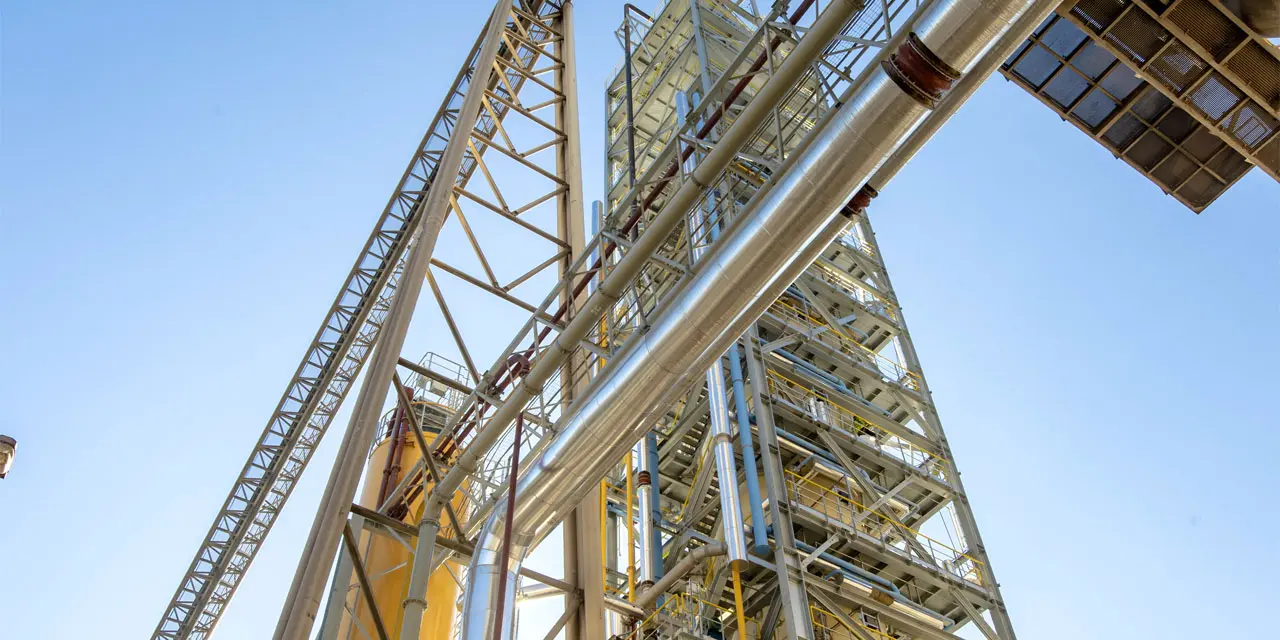 Industriekomplex mit einem Netzwerk aus Rohren und Trägern unter einem klaren blauen Himmel