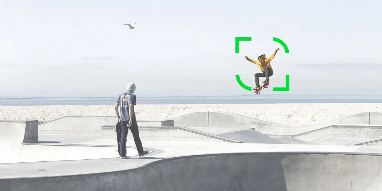 Zwei Skater in einem Skatepark aus Beton, einer springt, der andere hält sein Board. Im Hintergrund sind das Meer und eine Möwe zu sehen.