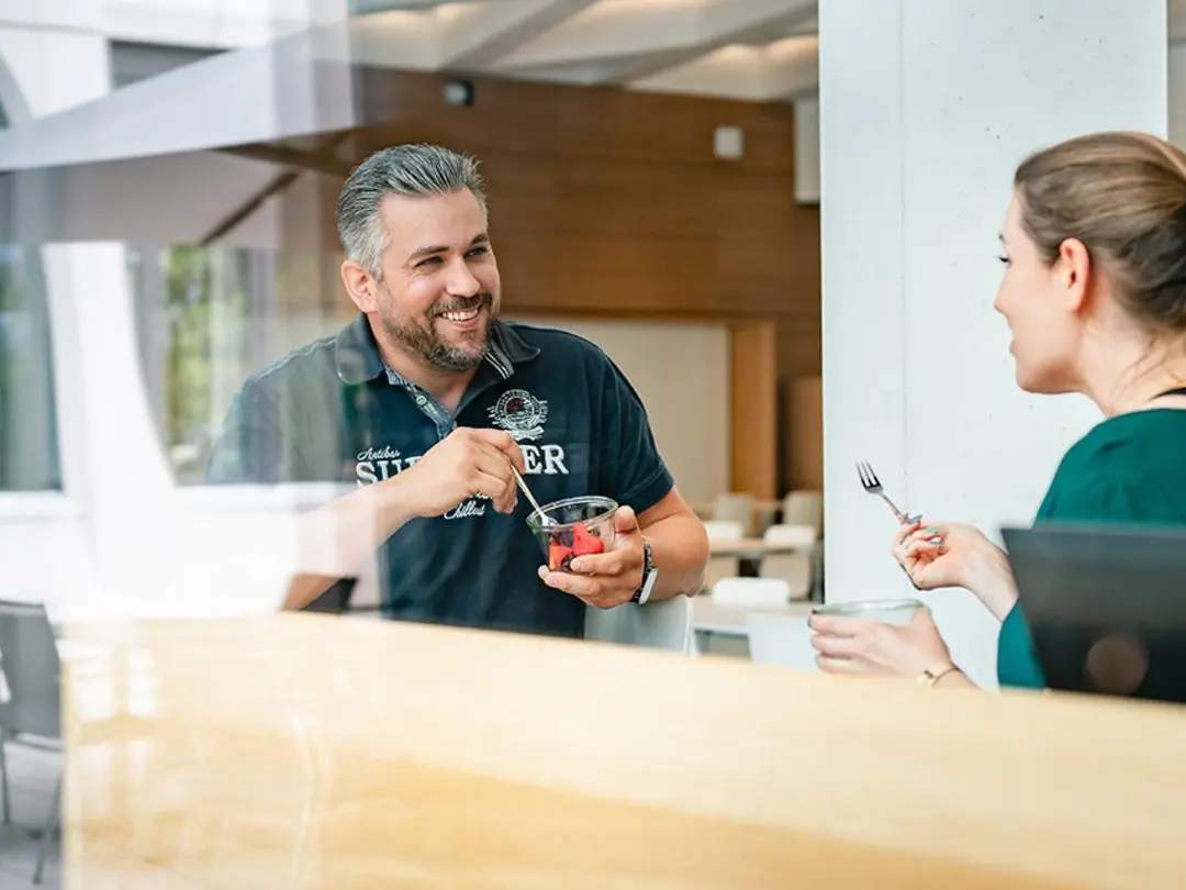 Zwei Kolleg*innen sitzen und unterhalten sich in der Cafeteria