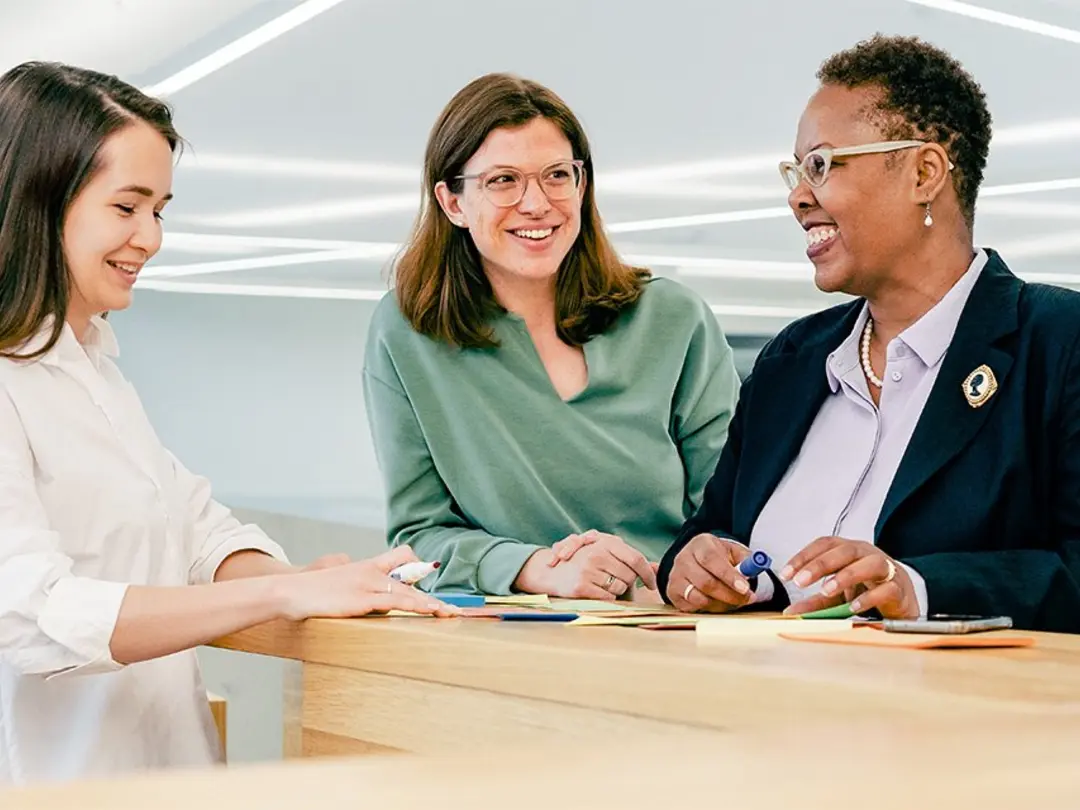 Three women standing in an office, talking with each other