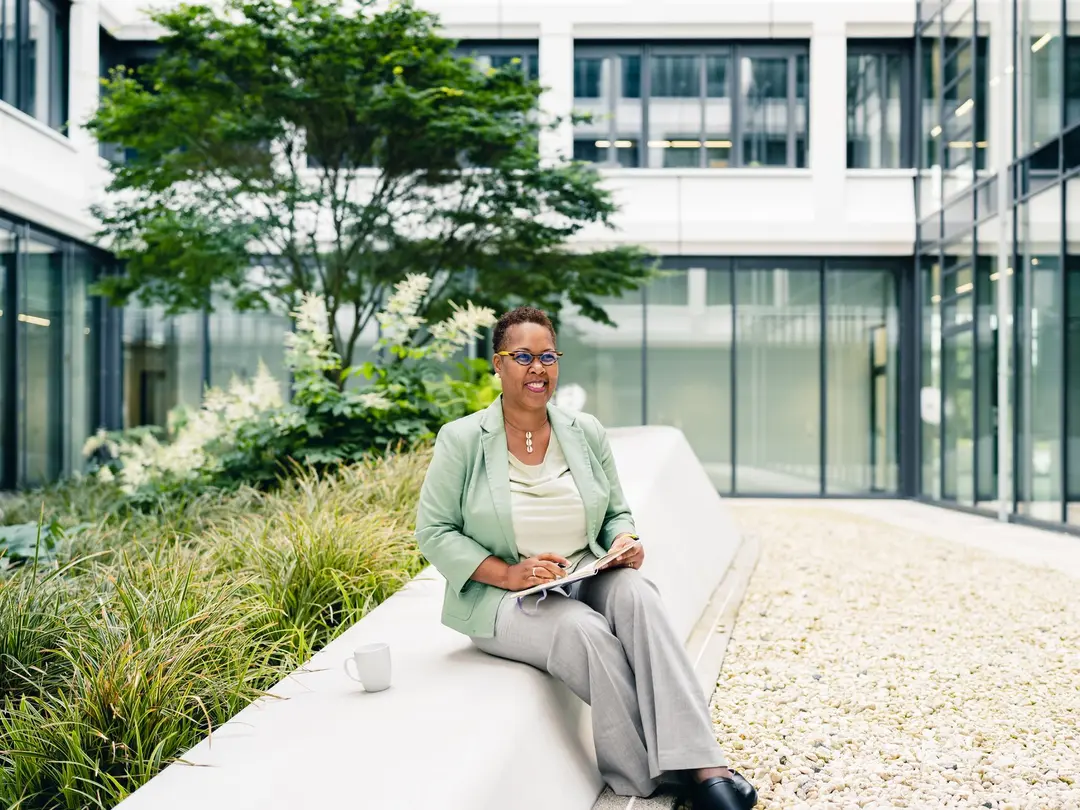 Woman sitting in a green courtyard taking notes