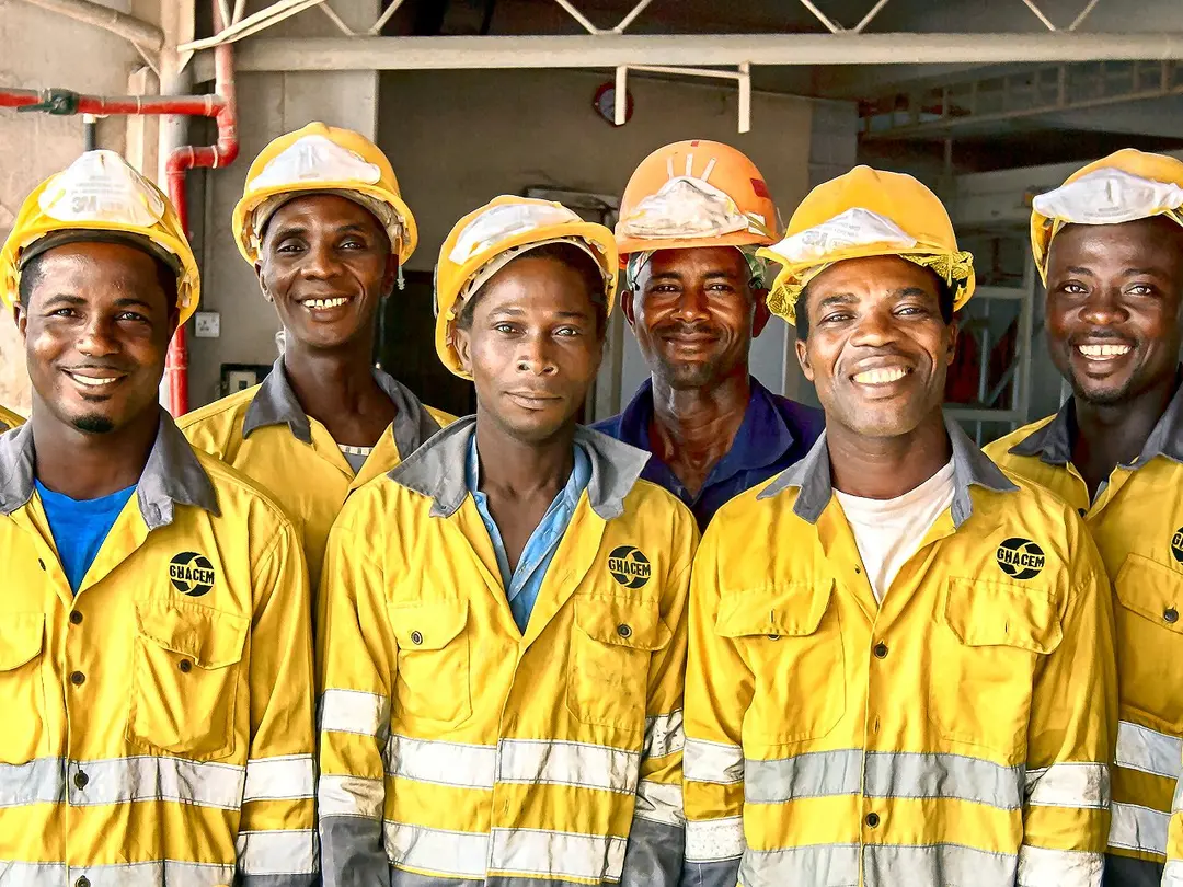Gruppe von Bauarbeitern in Sicherheitskleidung und Helmen in einem Zementwerk