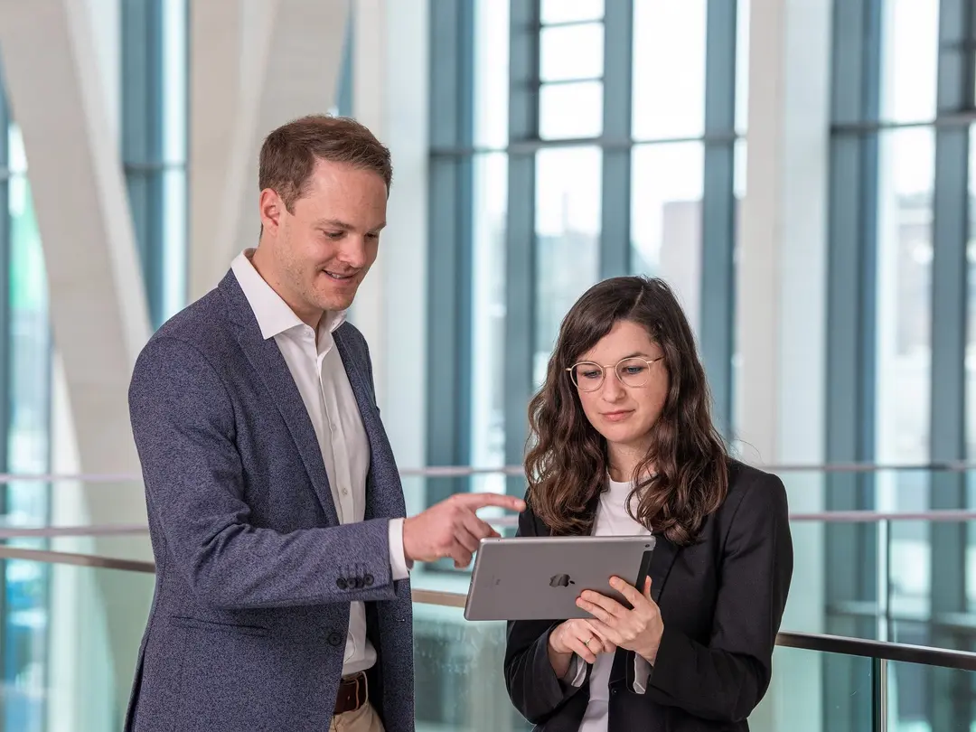 Ein Mann zeigt auf ein iPad, das iPad wird von einer Frau gehalten