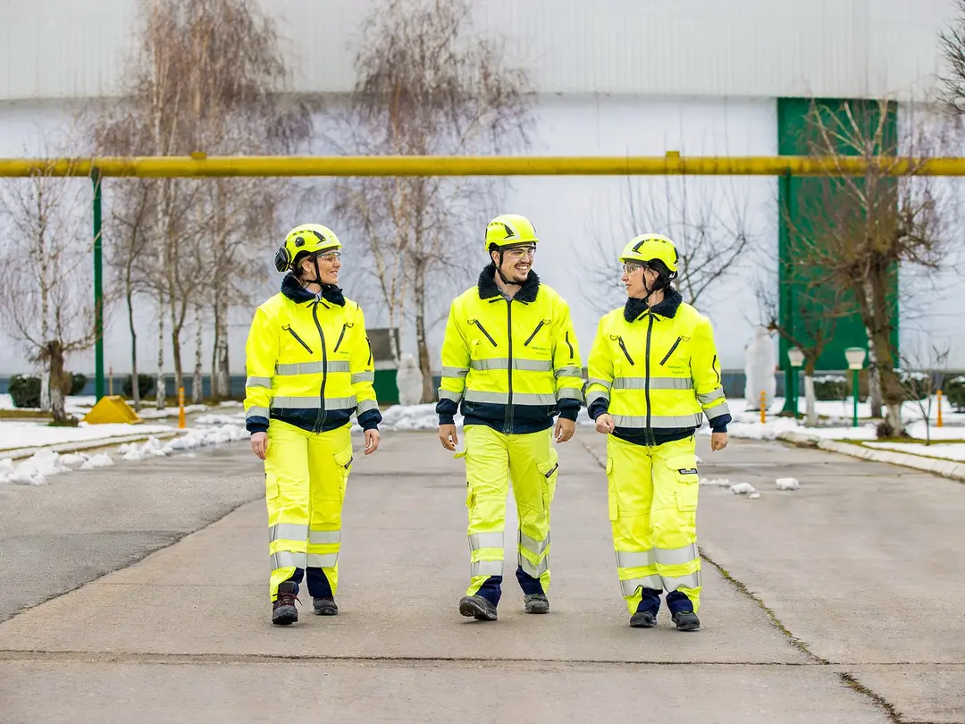 Drei Mitarbeitende in gelber Schutzkleidung, zwei davon weiblich, einer männlich