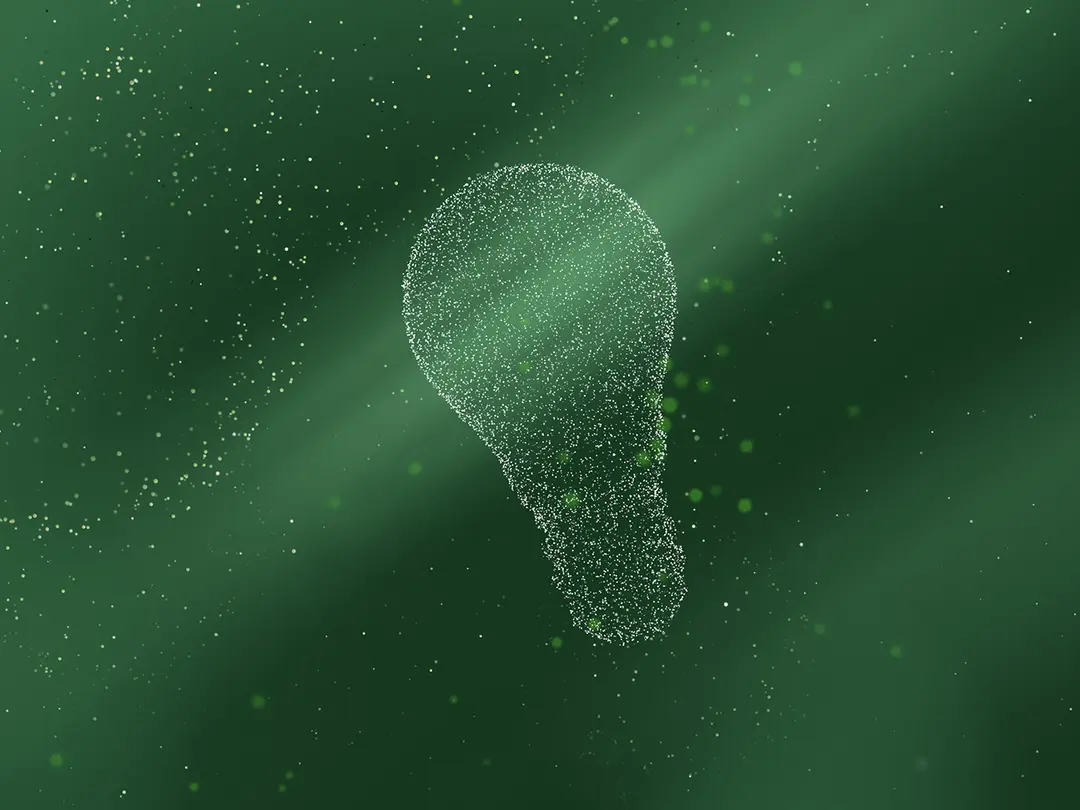 A lightbulb shape formed by green particles on a dark green background.