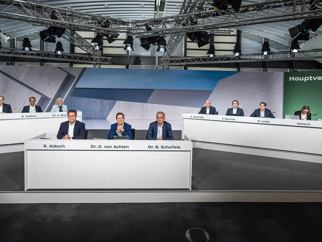 Personen an einem Konferenztisch bei einer Hauptversammlung von Heidelberg Materials.