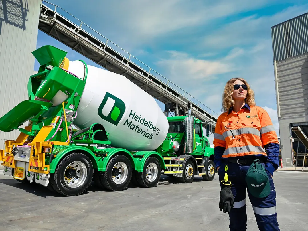 A construction worker stands near a Heidelberg Materials branded ready-mixed truck at a cement plant.
