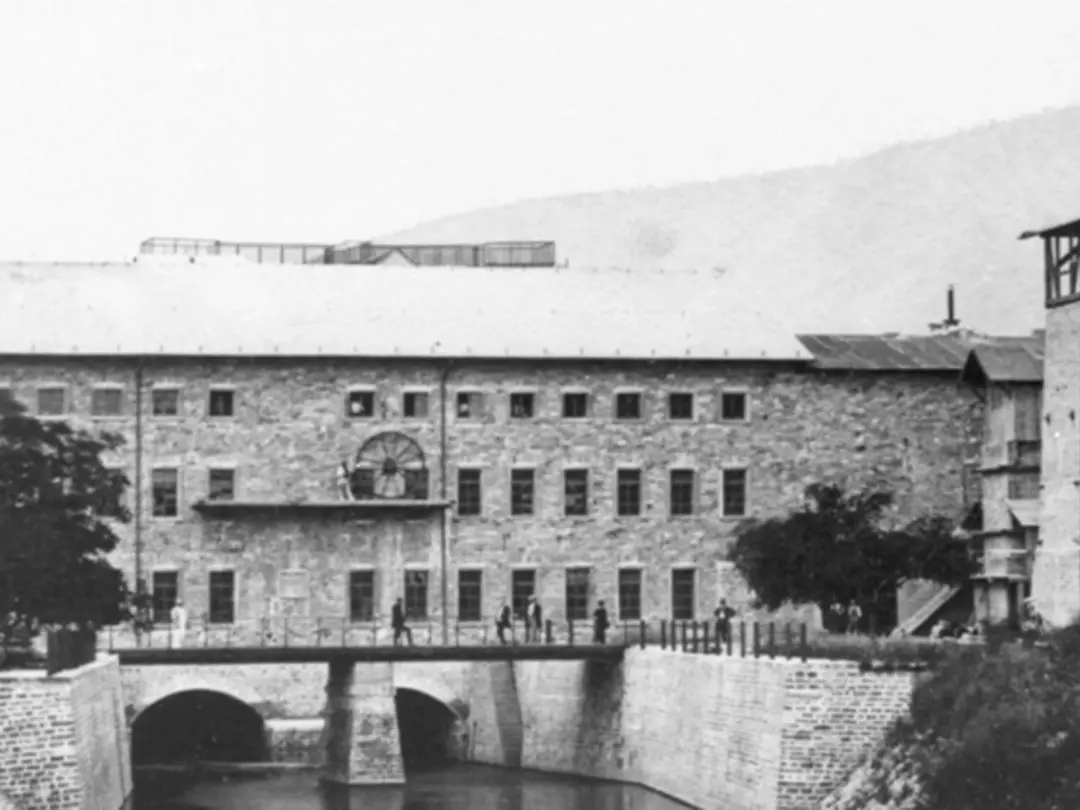 Historisches Foto eines mehrgeschossigen Gebäudes an einem Fluss