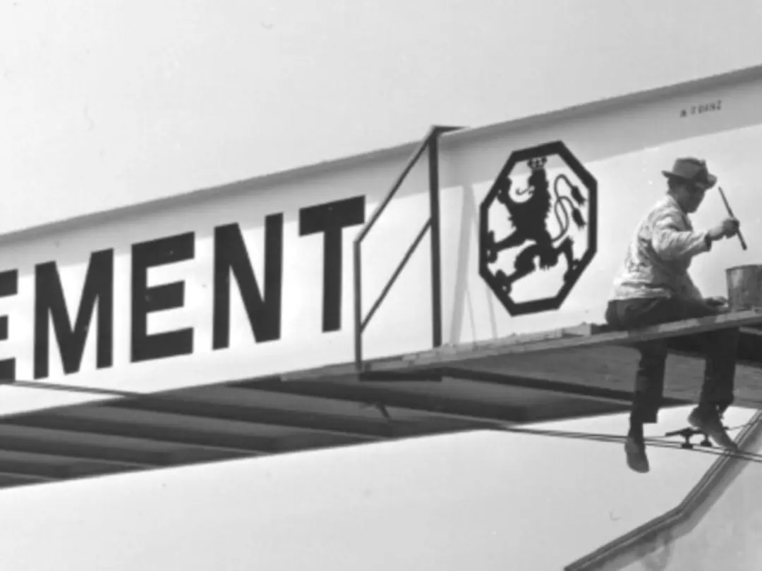 Ein Arbeiter sitzt auf einem Stahlträger mit der Aufschrift Heidelberger Zement.