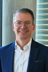 Robert Adolph in front of a concrete pillar and a window with a view of the Neckar