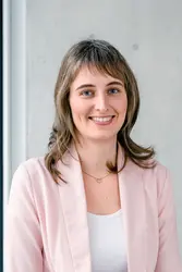 Annika Fuchs in hellrosa Blazer vor einer Sichtbetonwand