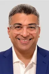 Man wearing a blue blazer over a white collared shirt.