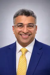 Nimit Kamdar wearing a blue suit, white shirt, and yellow tie.