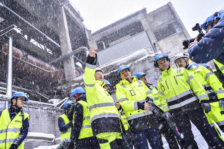 Men in work clothes and helmets visit a cement plant