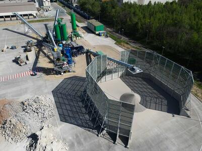Industrial site with aggregate storage bins, conveyor systems, and silos.
