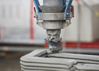 A 3D concrete printer creating a layered wall structure