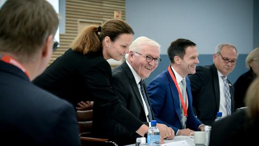 Federal President Steinmeier and Dominik von Achten are sitting in high spirits among the other participants at a conference table.